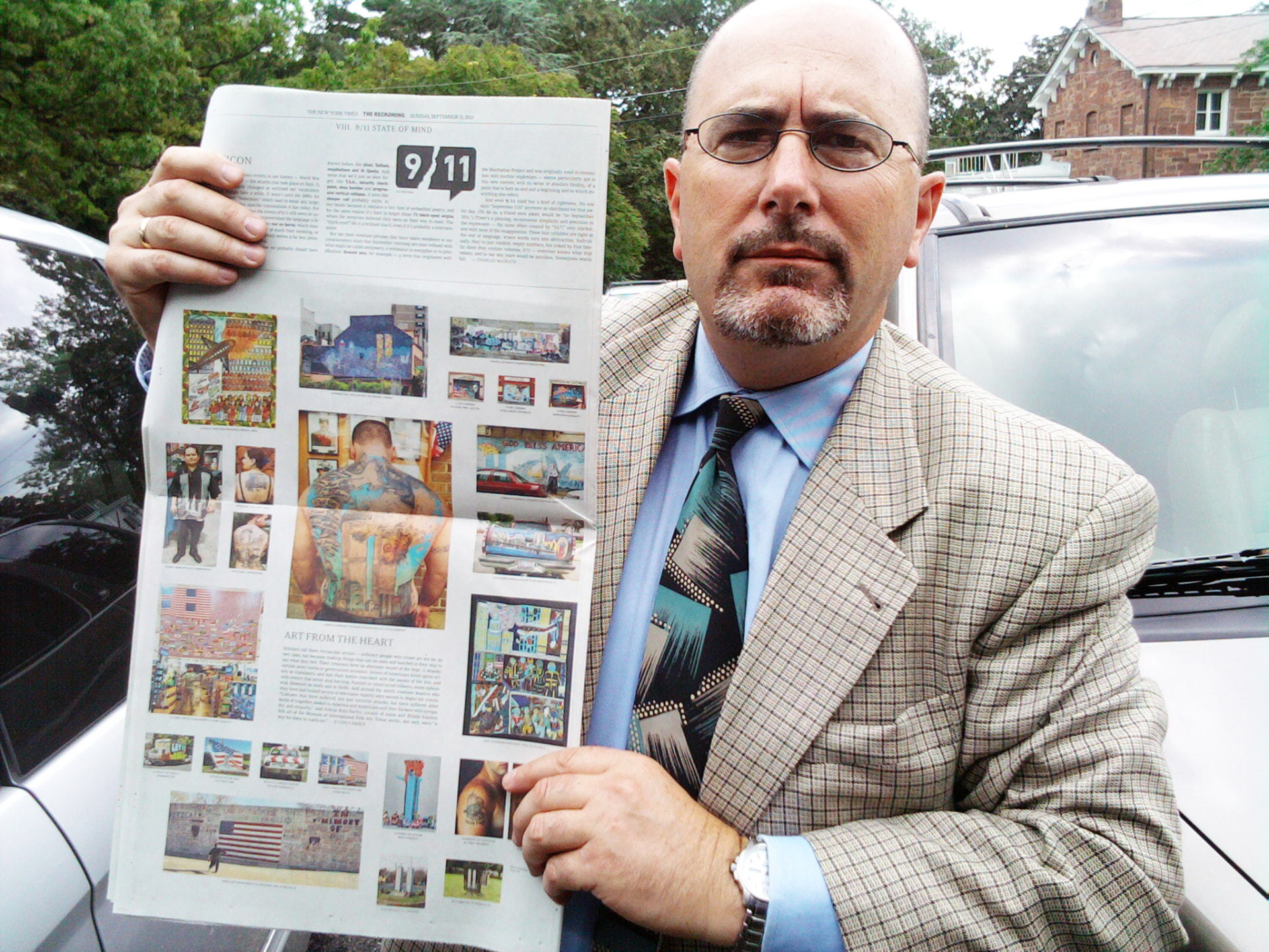 Jonathan C. Hyman holding a New York Times spread of his 9/11 vernacular art photographs