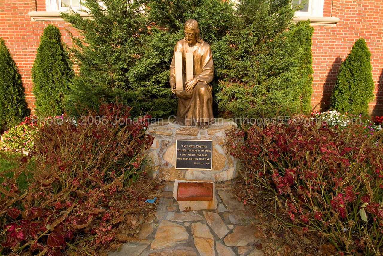 Bronze statue of Jesus embracing the twin towers in a Brooklyn garden memorial with an Isaiah inscription
