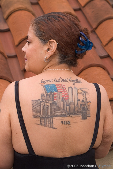 A woman's back tattooed with the New York skyline, twin towers, an American flag, and the words 'Gone but not forgotten, 9-11-01'