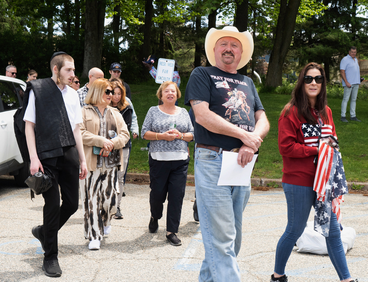 Attendees arriving outside a Trump rally in Suffern, New York, including a man in a cowboy hat and a woman carrying an American flag